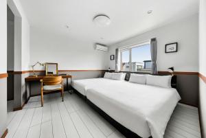 a bedroom with a bed and a desk and a window at The Shelbourne Furano in Furano