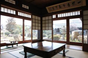 Okayama Hostel Igusa في Hayashima: غرفة مع طاولة في غرفة مع نوافذ