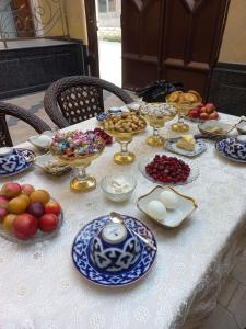 a table with plates and bowls of food on it at JOMIY Guest House in Margilan