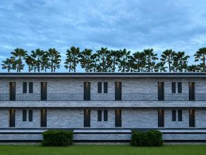 a building with palm trees in the background at The 50th Uthai Thani in Uthai Thani