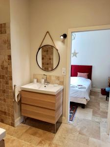 a bathroom with a sink and a bed and a mirror at Tournefeuille La Cure in Saint-Émilion