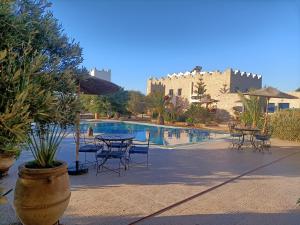 a pool with tables and chairs next to a building at Room in Villa Dar Albatros in Sidi Kaouki