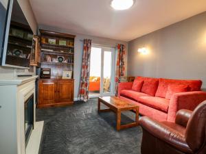 a living room with a red couch and a fireplace at Pinecote Cottage in Nottingham