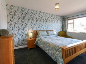 a bedroom with a bed with blue floral wallpaper at Pinecote Cottage in Nottingham