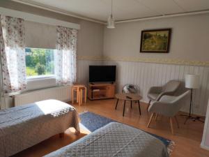 a bedroom with a bed and a television and a chair at Guesthouse Veteli in Veteli