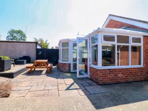 a greenhouse on the side of a house with a picnic table at Pinecote Cottage in Nottingham