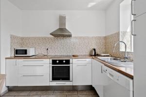 a white kitchen with a sink and a microwave at Green House Copenhagen in Copenhagen +9 photos
