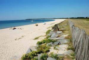 a sandy beach with a wooden fence and the ocean at Au coeur du golfe in Sarzeau +1 photo