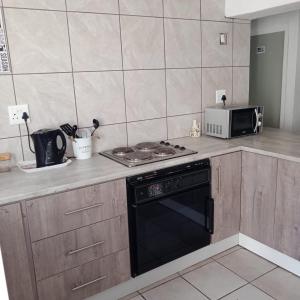 a kitchen with a stove and a microwave at Arniston Cottage in Arniston