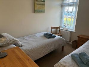 a bedroom with two beds and a table and a window at 10 The Downs, Thurlestone overlooking Burgh Island in Kingsbridge