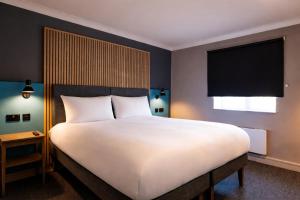 a bedroom with a large white bed with a large window at Village Hotel Birmingham Dudley in Dudley +37 photos