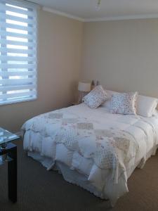 a bedroom with a white bed with pillows and a window at Vista Laguna in San Pedro de la Paz