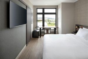 a bedroom with a bed and a table and a window at Moxy Portland Thompson's Point in Portland
