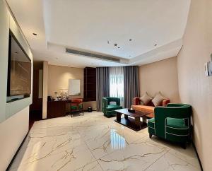 a living room with a couch and green chairs at Phoenix Crowne Vinh Hotel in Vinh