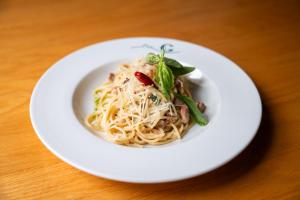 ein weißer Teller Pasta auf einem Holztisch in der Unterkunft Hotel Galant Lednice in Lednice