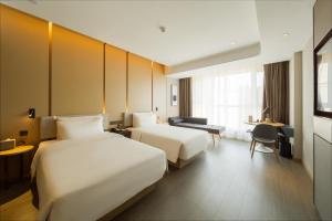 a hotel room with two beds and a desk at Atour Hotel Changchun Ecological Square in Changchun
