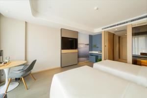a bedroom with a white bed and a desk and a chair at Atour Hotel Changchun Ecological Square in Changchun
