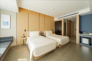 two beds in a hotel room with a fireplace at Atour Hotel Changchun Ecological Square in Changchun +3 photos