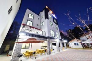 a large white building with tables and an umbrella at Samcheok blossom pension in Samcheok