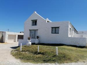 a white house on the side of a road at Arniston Cottage in Arniston