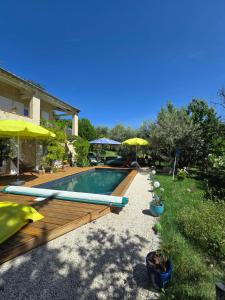 a swimming pool in a yard with umbrellas at A l'Orée des Oliviers in Venterol