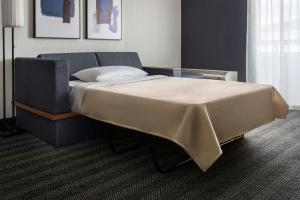 a bedroom with a bed with a blanket on it at Courtyard Syracuse Carrier Circle in East Syracuse +17 photos