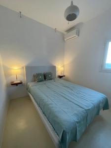 a bedroom with a bed with a blue comforter and two lamps at Silver Lining in Akrotiri