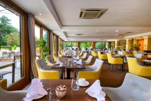 a restaurant with tables and yellow chairs and windows at Shendish Manor Hotel & Golf Course in Hemel Hempstead