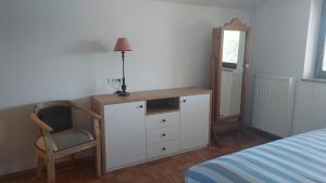 a bedroom with a dresser and a chair and a mirror at Apartma AURA in Slovenske Konjice
