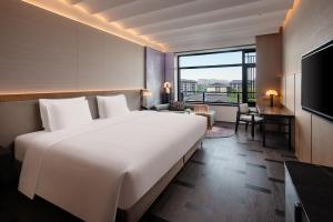 a hotel room with a large white bed and a desk at Bristoria Hotel Yangzhou in Yangzhou