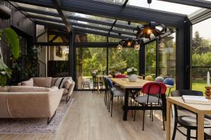 a living room with a conservatory with a table and chairs at Willa Magnolia - pokoje i apartamenty - rowery - plac zabaw MONTESSORI - basen - pokój zabaw in Jantar