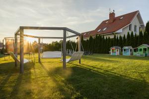 a swing set in a yard with a house at Willa Magnolia - pokoje i apartamenty - rowery - plac zabaw MONTESSORI - basen - pokój zabaw in Jantar