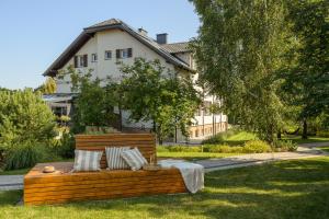 a wooden bench sitting in the grass in front of a house at Willa Magnolia - pokoje i apartamenty - rowery - plac zabaw MONTESSORI - basen - pokój zabaw in Jantar