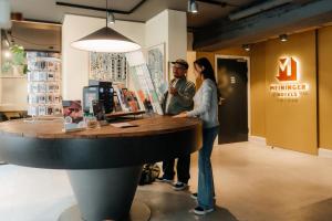 two people standing at a counter in a store at MEININGER Hotel Copenhagen in Copenhagen