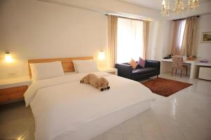 a dog laying on a large white bed in a bedroom at Samunthitar Resort in Khao Kho