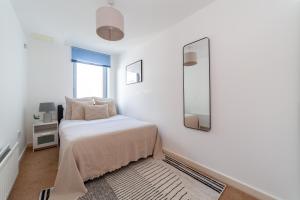 a white bedroom with a bed and a mirror at Spacious 2 Bed Apartment in Stratford in London
