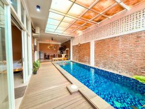 a swimming pool in a room with a brick wall at Emka Family Villa Malang in Malang