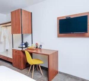 a desk with a yellow chair and a tv on a wall at Hudson Resorts in Pondūr