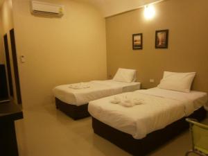 two beds in a hotel room with at Surintara Resort in Surin