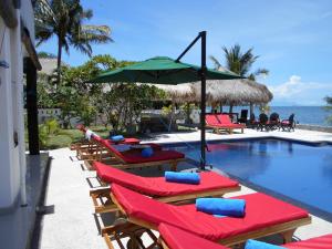 a group of chairs and umbrellas next to a swimming pool at Silver Fern Beach Retreat in Sekotong