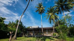 a house with palm trees in front of it at Chababaancham Resort in Amphawa