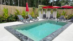 a swimming pool with chairs and umbrellas in a backyard at Aranya Bliss Villa 105 in Ban Madua Wan