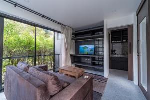 a living room with a couch and a large window at Aranya Bliss Villa 105 in Ban Madua Wan