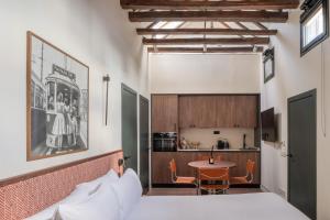 a bedroom with a bed and a table and a kitchen at POSTCODE Chueca in Madrid