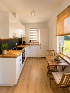 a kitchen with white cabinets and a wooden table at Brajnickie Zacisze in Brajniki