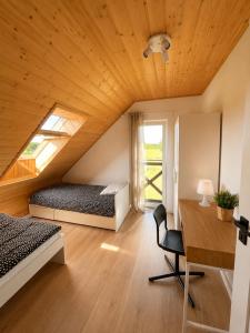 a attic bedroom with two beds and a desk at Brajnickie Zacisze in Brajniki