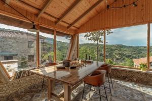 a dining room with a table and chairs and large windows at La Villa de Madeleine - Stone Villa with outdoor hot tub in Arcadia, Peloponnese in Áyios Ioánnis