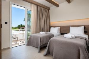 two beds in a hotel room with a balcony at Sam's Faliraki in Faliraki +32 photos