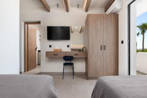 a bedroom with two beds and a desk with a television at Sam's Faliraki in Faliraki