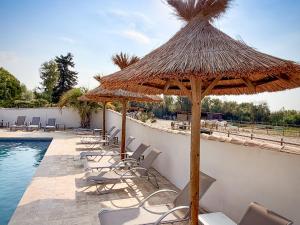 a group of chairs and umbrellas next to a swimming pool at Hotel Mas Des Barres in Saintes-Maries-de-la-Mer
